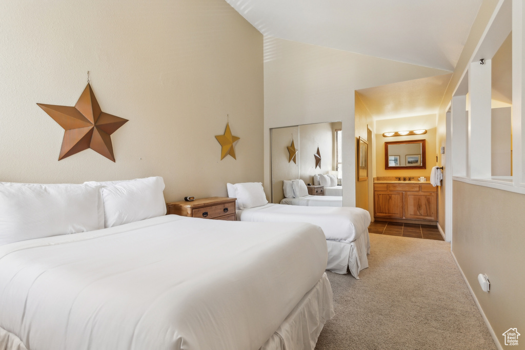 Bedroom with carpet flooring, lofted ceiling, ensuite bath, and baseboards