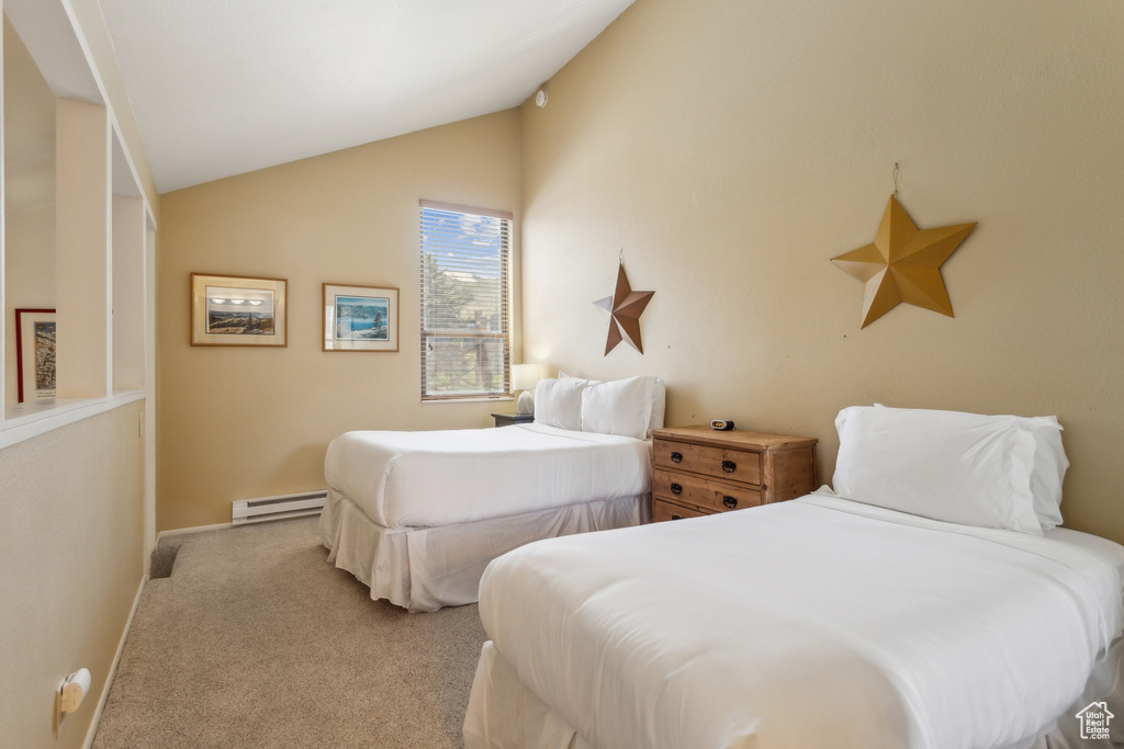 Carpeted bedroom featuring a baseboard heating unit, vaulted ceiling, and baseboards