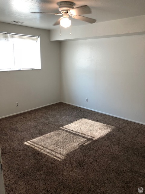 Carpeted empty room featuring a ceiling fan and baseboards