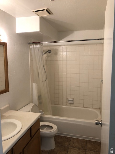 Bathroom featuring tile patterned floors, vanity, shower / tub combo, toilet, and a textured wall