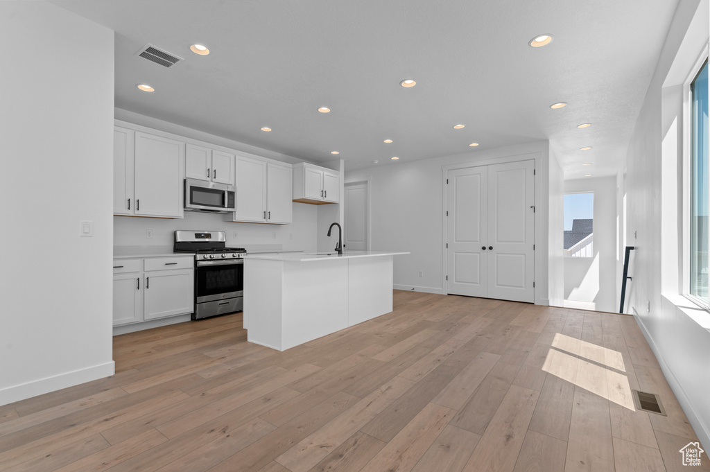 Kitchen featuring stainless steel appliances, white cabinetry, recessed lighting, light countertops, and a sink