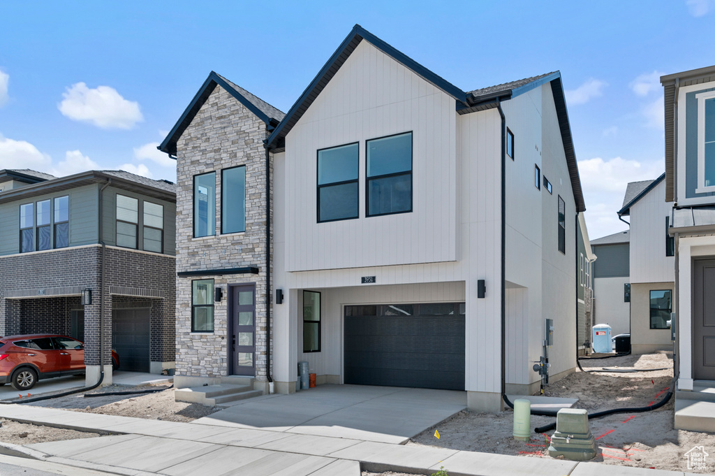 Contemporary house featuring a garage, stone siding, and concrete driveway