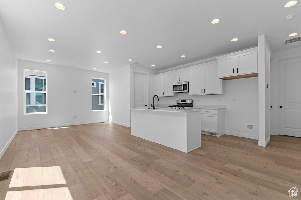 Kitchen with stainless steel appliances, recessed lighting, baseboards, white cabinetry, and light wood-style flooring