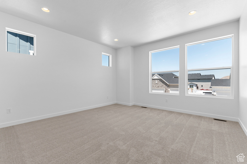 Empty room featuring light carpet, recessed lighting, and baseboards