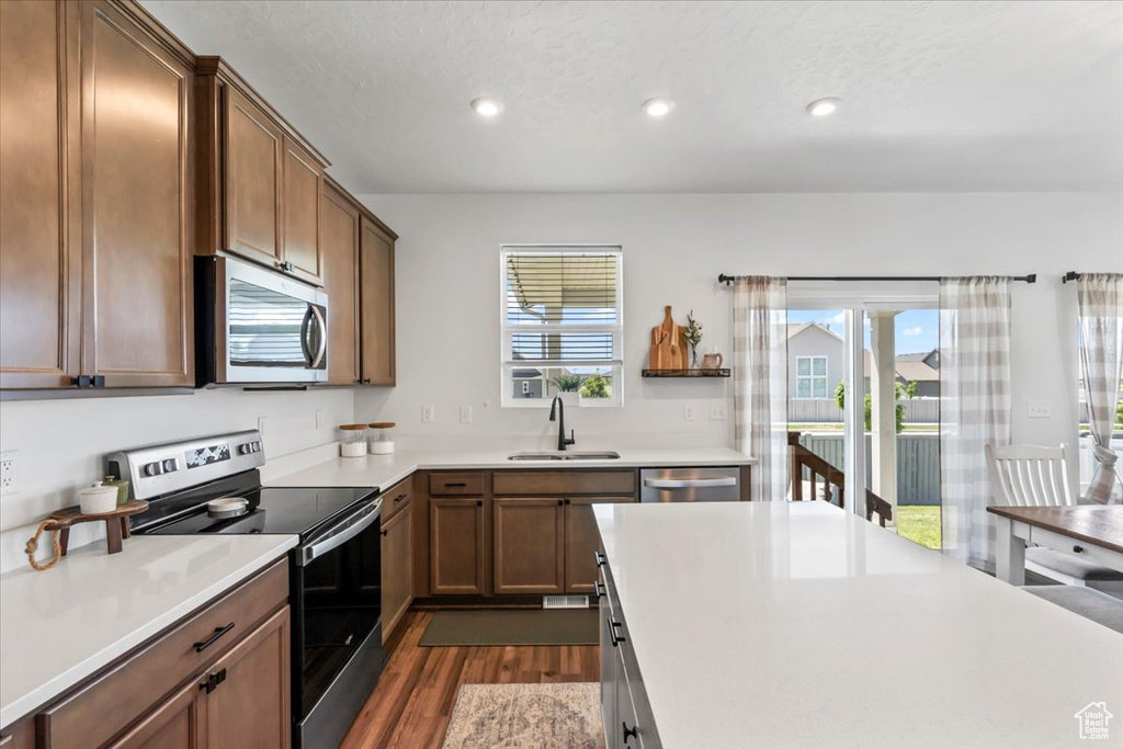 Kitchen with appliances with stainless steel finishes, a sink, dark wood finished floors, recessed lighting, and light countertops