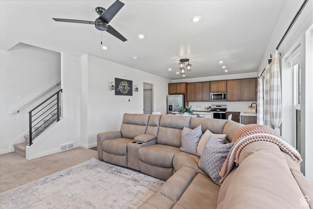 Living room with light colored carpet, recessed lighting, stairway, baseboards, and a ceiling fan