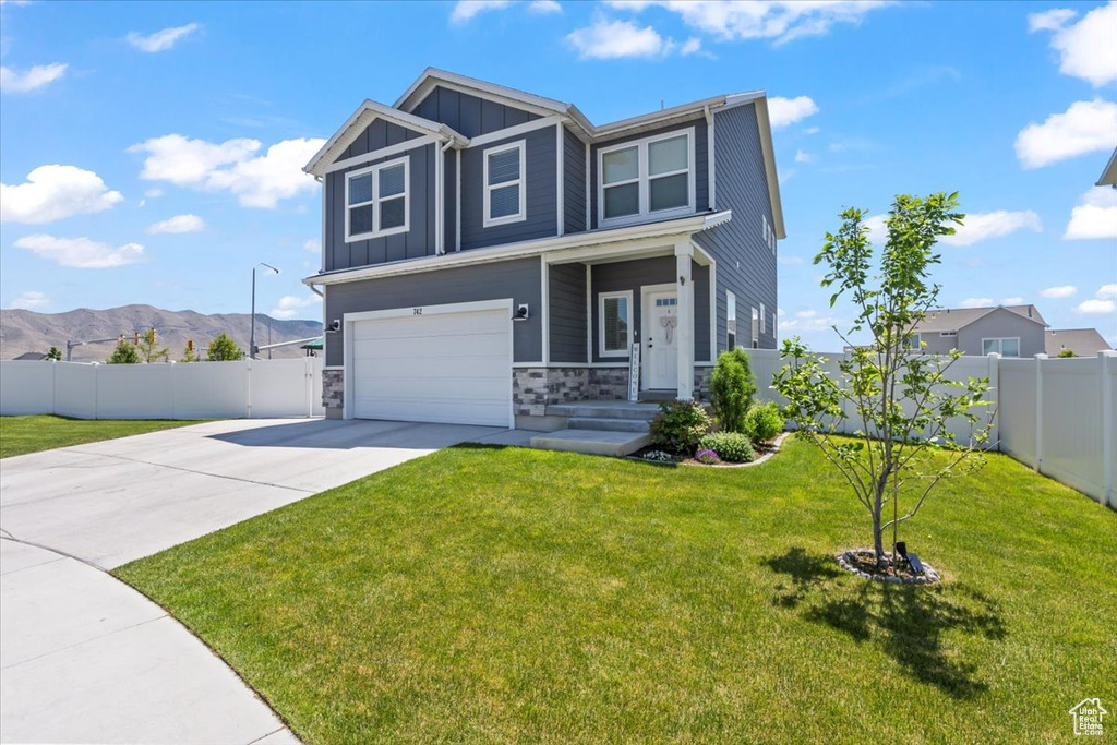 Craftsman-style home with board and batten siding, driveway, a garage, stone siding, and a mountain view