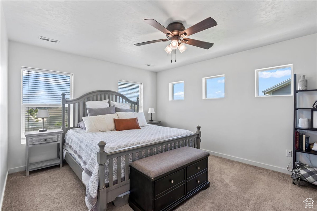 Bedroom featuring light colored carpet, baseboards, and a ceiling fan