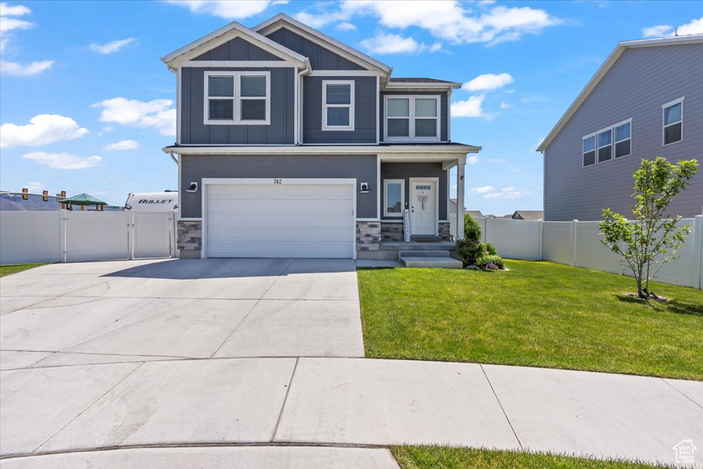 View of front of property with board and batten siding, driveway, a gate, and stone siding