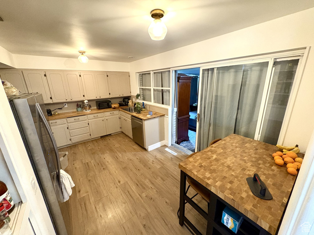 Kitchen with stainless steel appliances, light wood-style floors, white cabinets, and light countertops