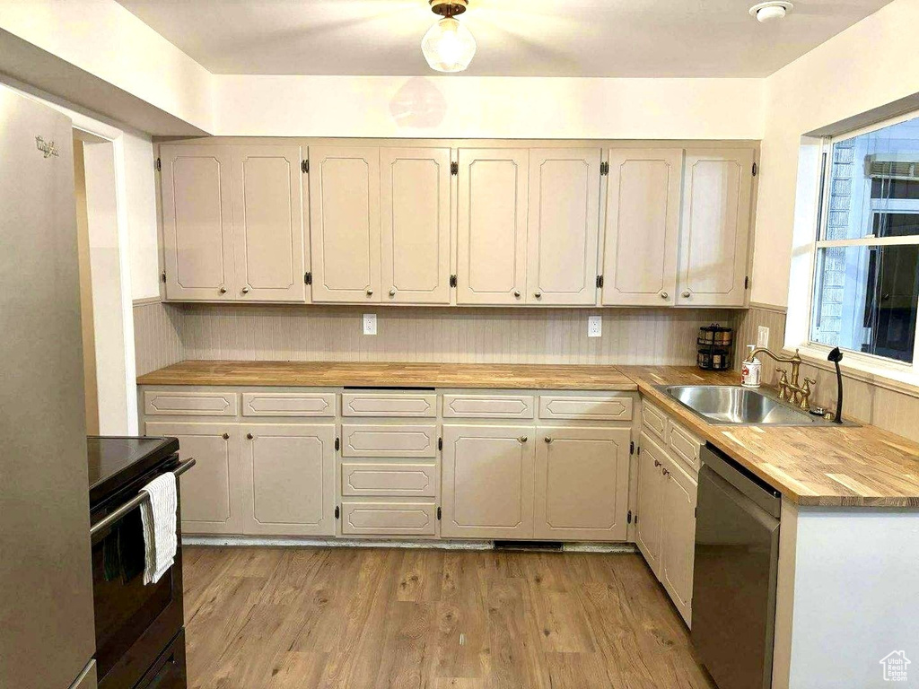 Kitchen with dishwasher, a sink, electric range, light wood finished floors, and light countertops