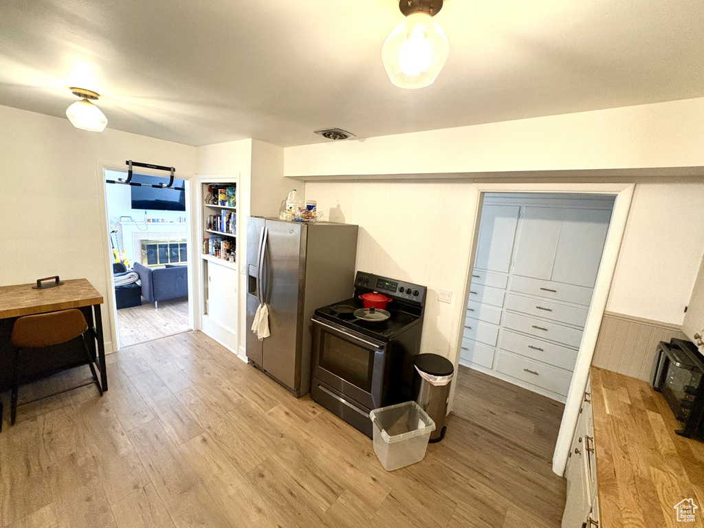 Kitchen featuring stainless steel appliances, light wood-style flooring, butcher block counters, and white cabinets