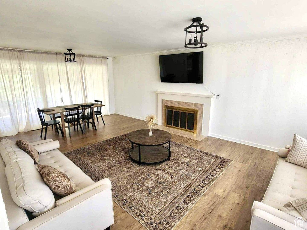 Living area featuring wood finished floors, a tiled fireplace, and baseboards