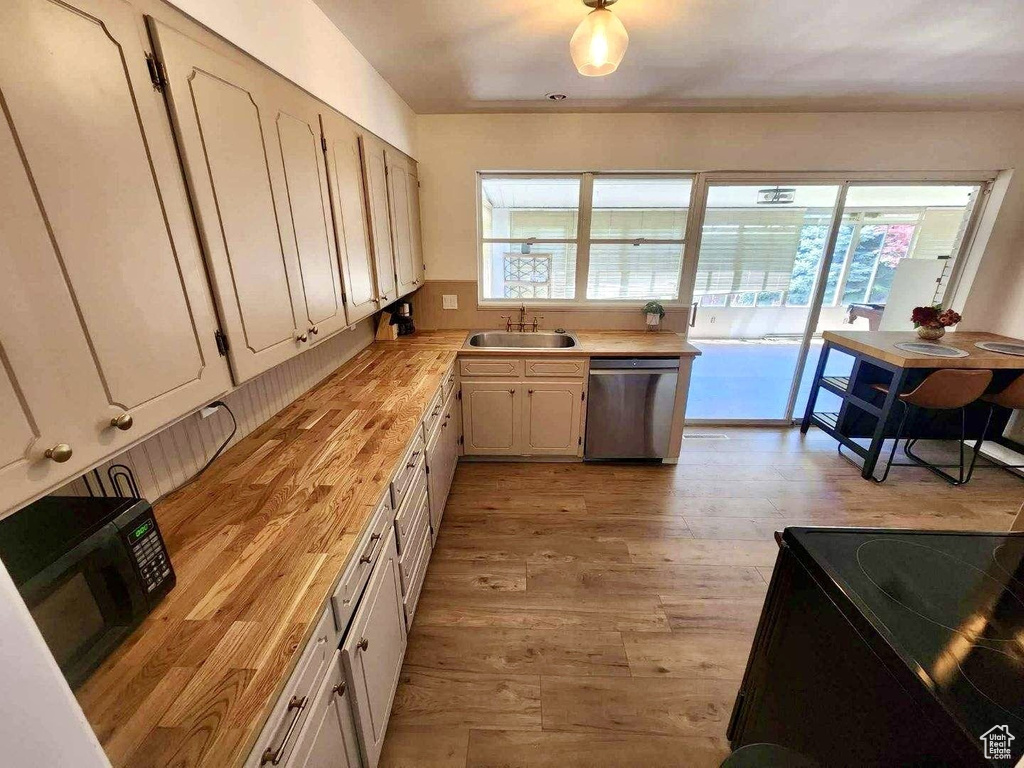 Kitchen featuring black appliances, a sink, light wood-type flooring, wooden counters, and white cabinets