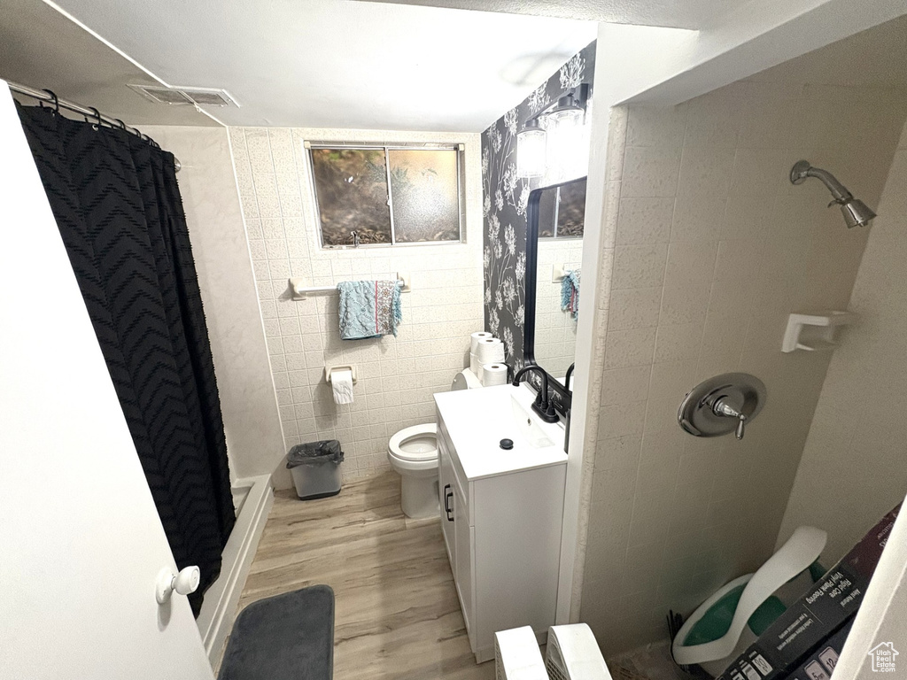 Full bath featuring vanity, a stall shower, wood finished floors, and toilet
