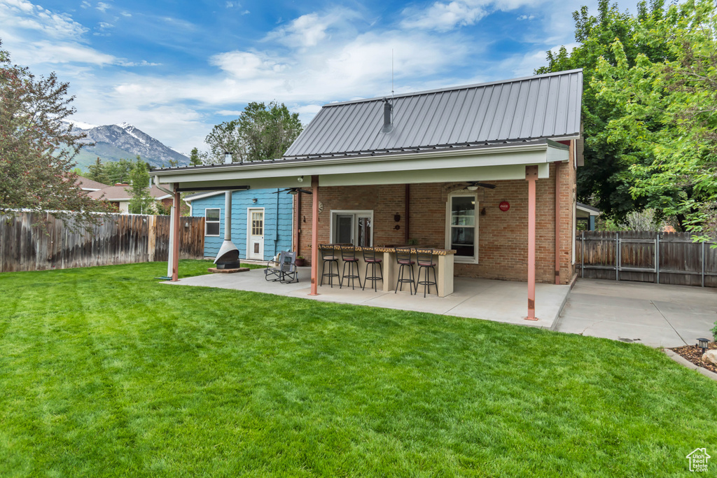Back of property with a patio, a mountain view, brick siding, and a ceiling fan