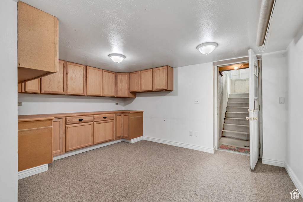 Kitchen featuring baseboards, light carpet, a textured ceiling, and light countertops
