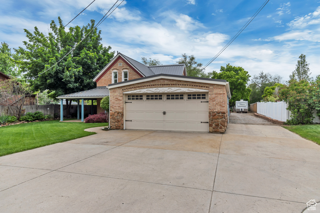 View of front of home featuring concrete driveway, metal roof, brick siding, an attached garage, and stone siding