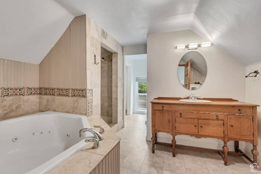 Full bath with vaulted ceiling, a jetted tub, vanity, and tiled shower