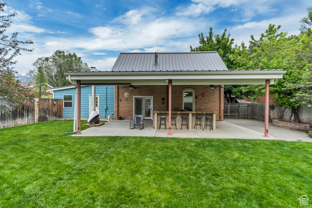 Back of property featuring ceiling fan, a patio, brick siding, and metal roof