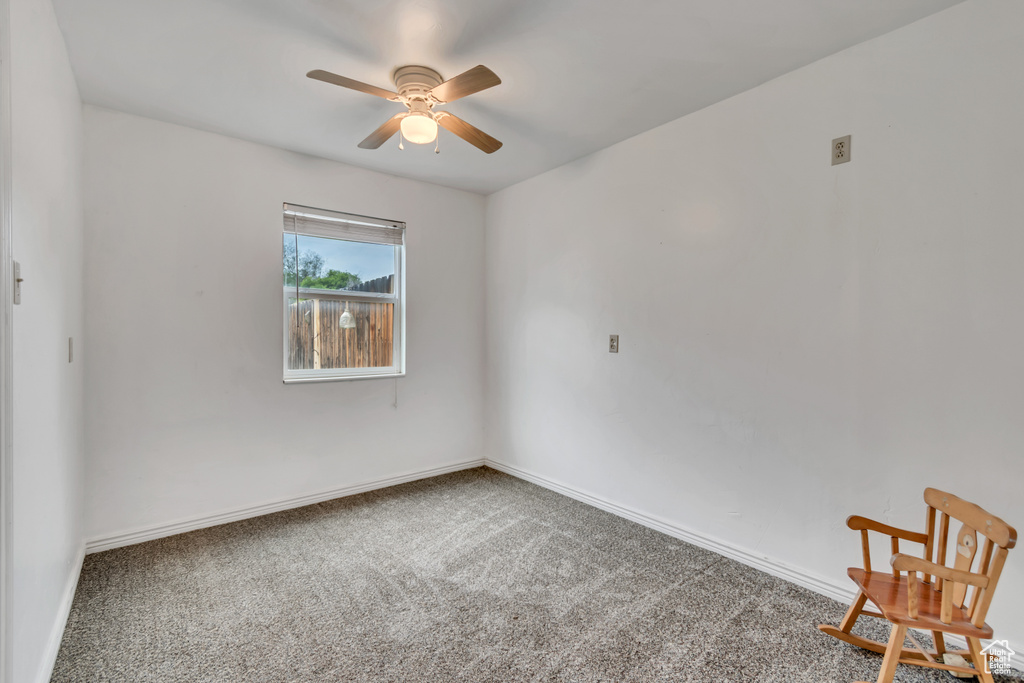 Carpeted empty room with a ceiling fan and baseboards