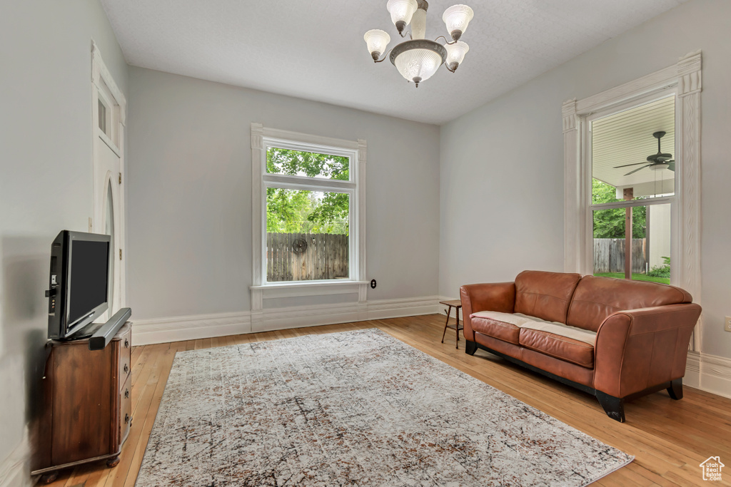 Living area with a chandelier, light wood-style flooring, and baseboards