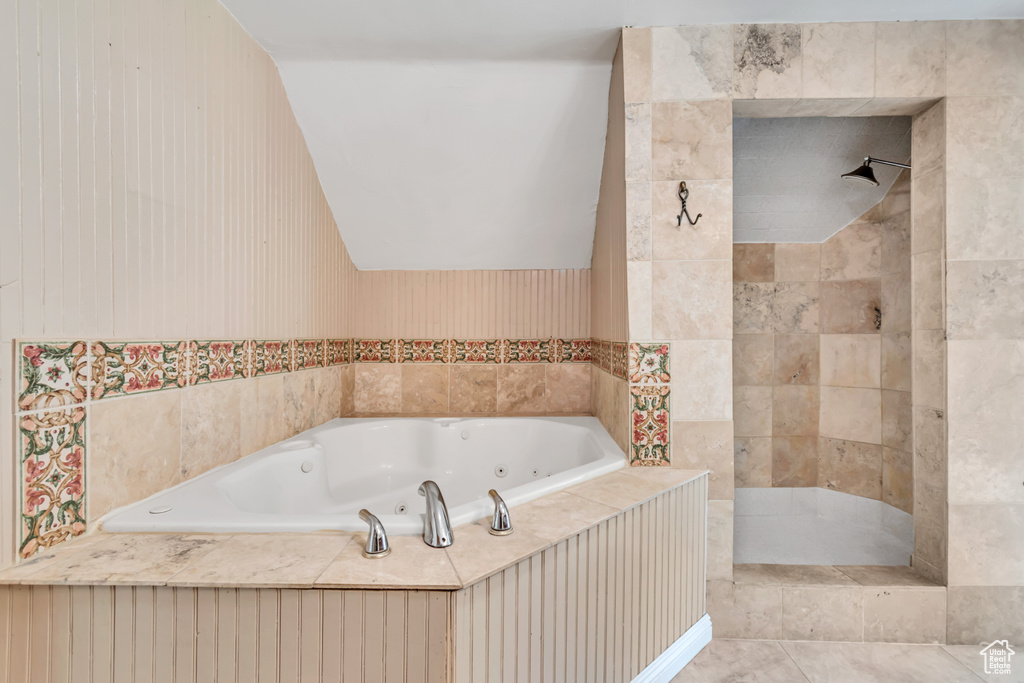 Bathroom featuring tiled shower and a tub with jets