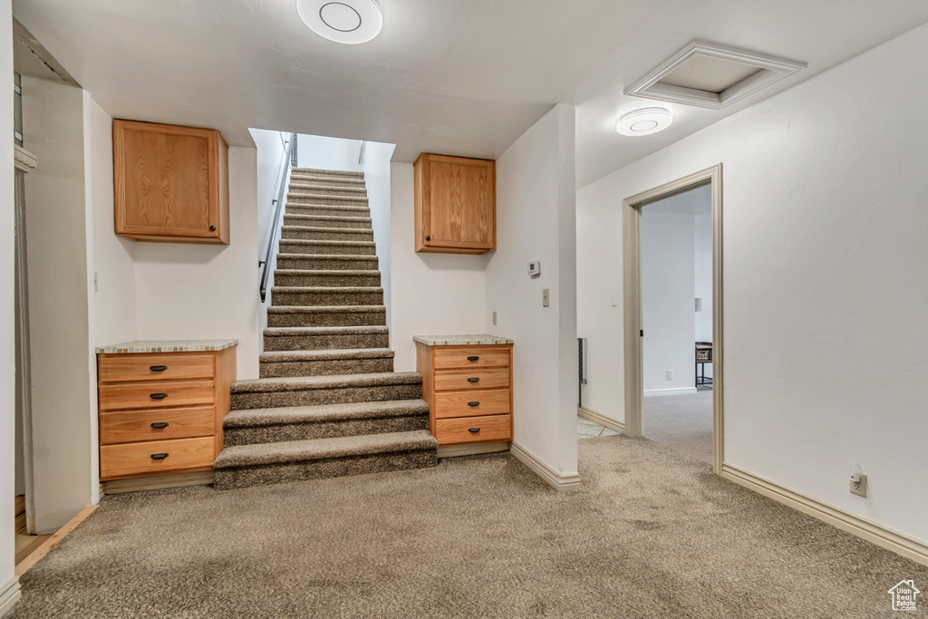 Below grade area with light carpet, baseboards, and stairs