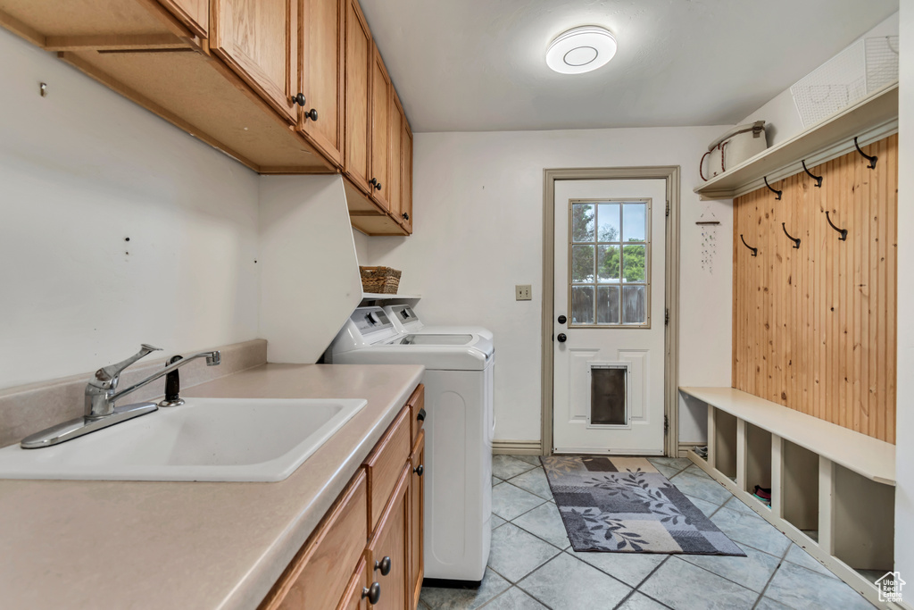 Laundry area with separate washer and dryer, light tile patterned floors, and cabinet space