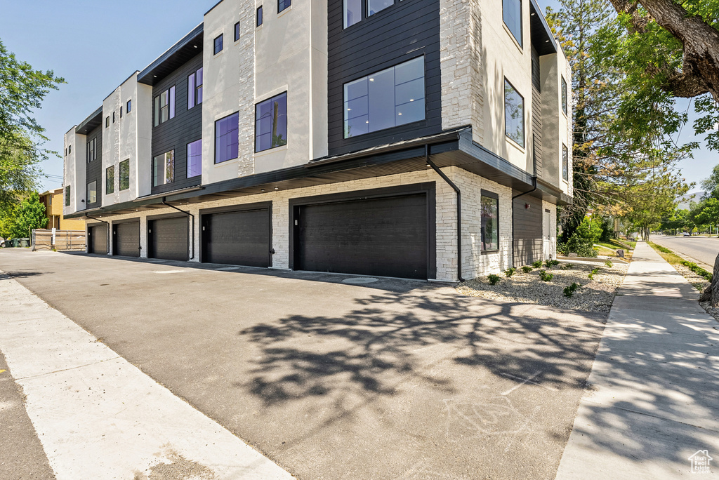 View of property exterior with driveway, a garage, and stone siding