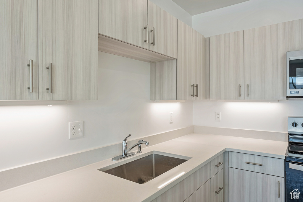 Kitchen featuring modern cabinets, appliances with stainless steel finishes, light countertops, and a sink
