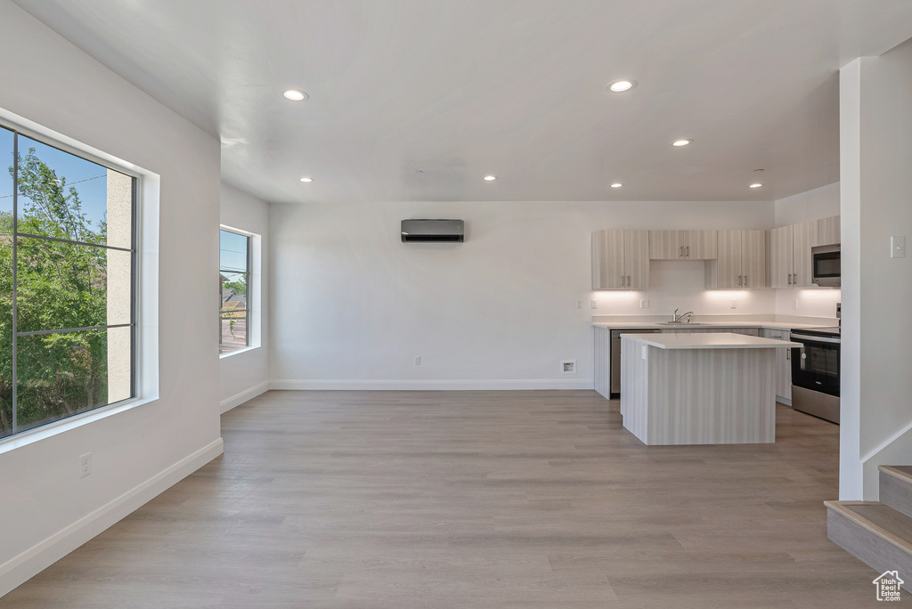 Kitchen with appliances with stainless steel finishes, a center island, a sink, light countertops, and recessed lighting