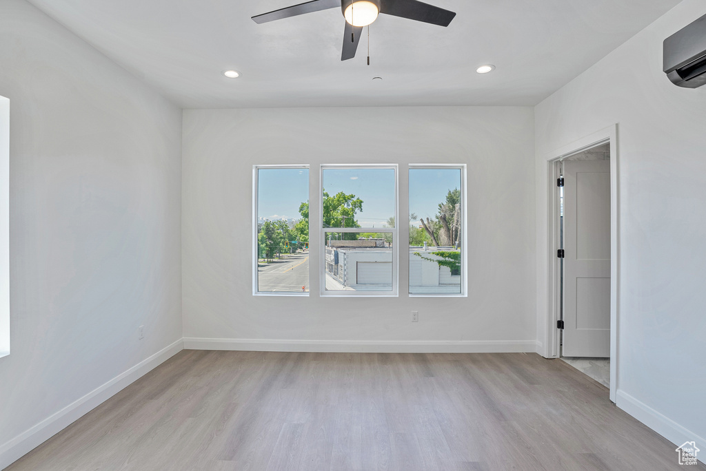 Unfurnished room featuring light wood finished floors, a wall mounted air conditioner, recessed lighting, baseboards, and ceiling fan