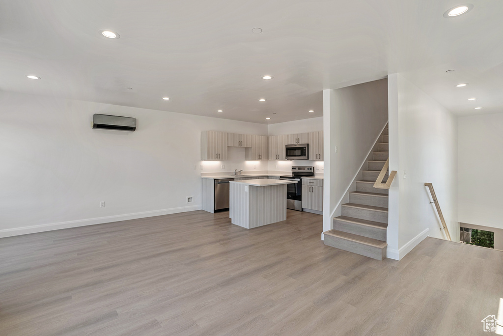 Kitchen with appliances with stainless steel finishes, a kitchen island, open floor plan, recessed lighting, and light countertops