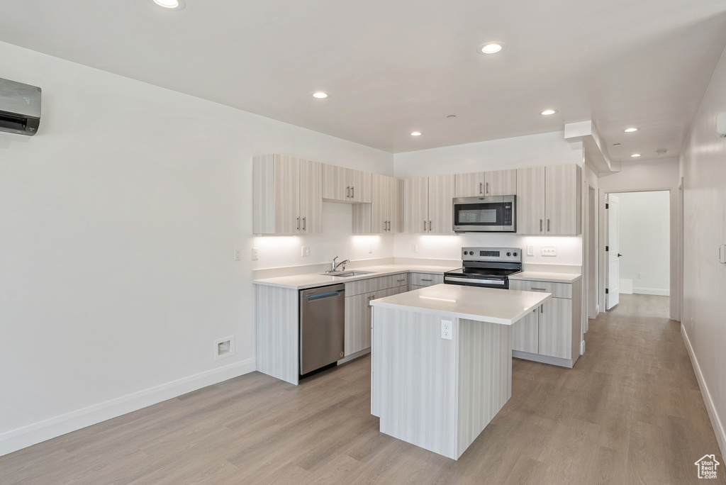 Kitchen featuring stainless steel appliances, a sink, a center island, light wood-style floors, and recessed lighting