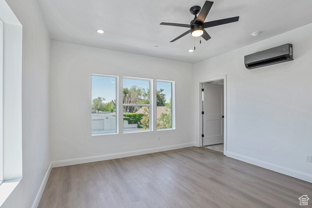 Spare room featuring a wall mounted AC, wood finished floors, recessed lighting, baseboards, and ceiling fan