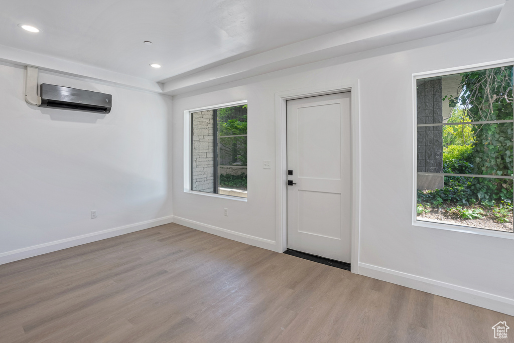 Entrance foyer with a wall unit AC, wood finished floors, baseboards, and recessed lighting
