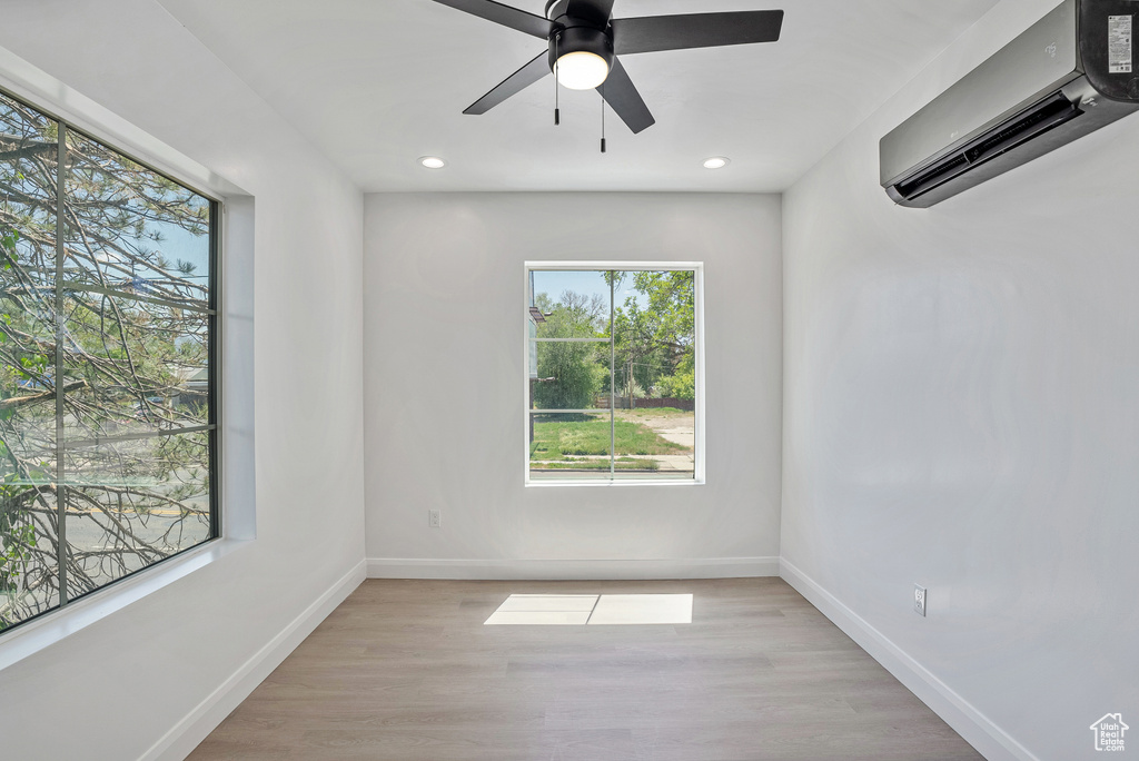 Unfurnished room featuring a wall mounted air conditioner, baseboards, a ceiling fan, recessed lighting, and light wood finished floors