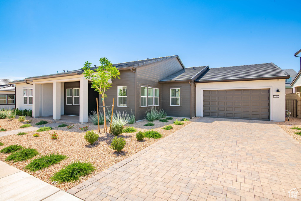 Ranch-style home with decorative driveway, a garage, and stucco siding