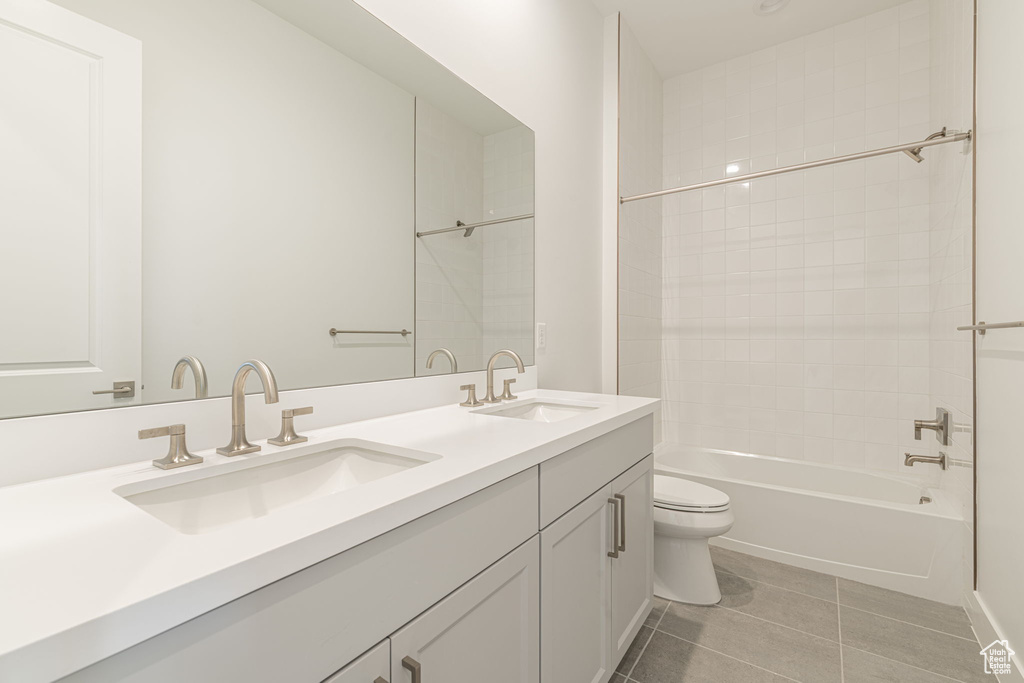 Bathroom with toilet, double vanity, tile patterned floors, and shower / bath combination