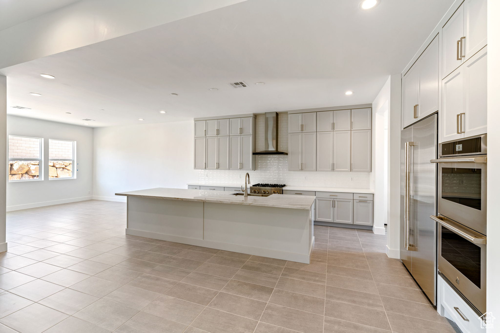 Kitchen featuring wall chimney exhaust hood, stainless steel appliances, decorative backsplash, light tile patterned flooring, and recessed lighting