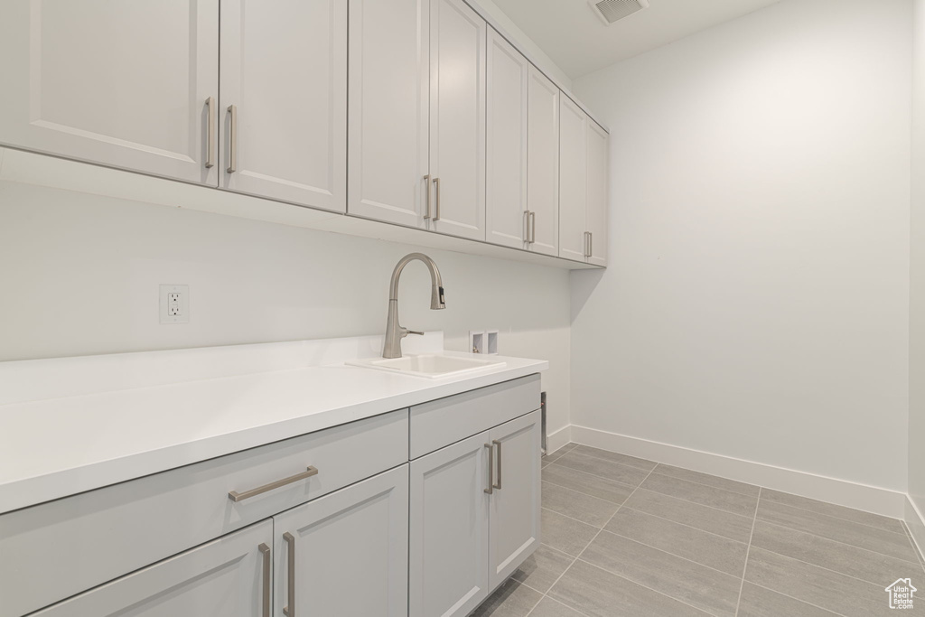 Laundry room with hookup for a washing machine, cabinet space, baseboards, and light tile patterned floors