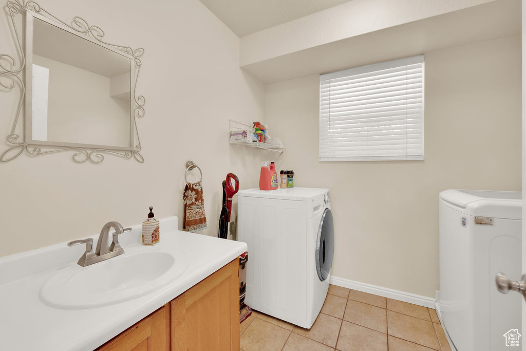 Laundry area with a sink, washing machine and clothes dryer, light tile patterned floors, and baseboards