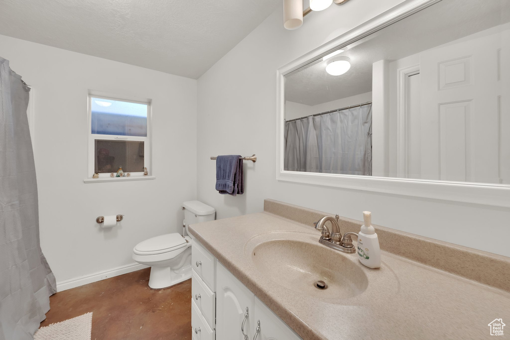 Bathroom featuring vanity, finished concrete floors, toilet, baseboards, and curtained shower