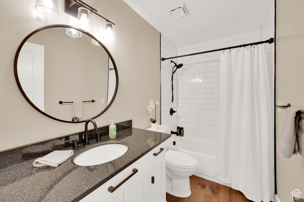 Full bath featuring toilet, vanity, shower / tub combo, and wood finished floors