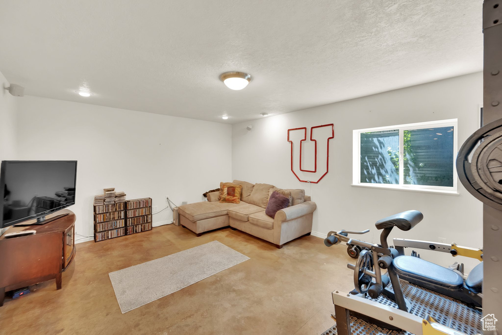 Living area featuring a textured ceiling, baseboards, and finished concrete floors
