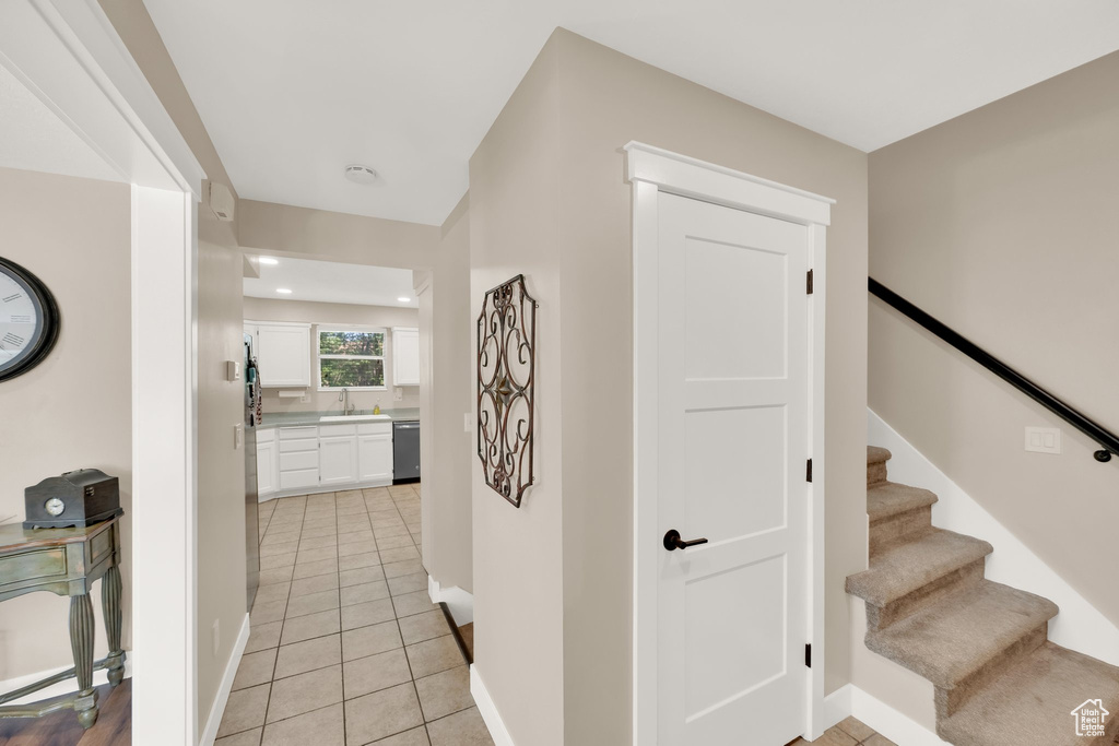 Corridor featuring light tile patterned floors, a sink, baseboards, stairway, and recessed lighting