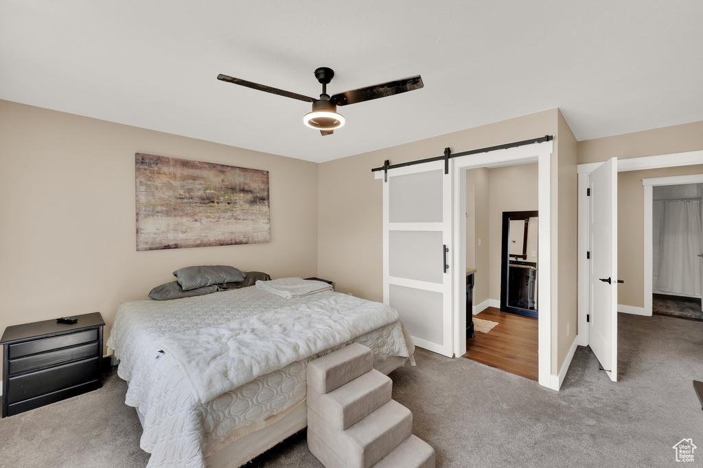 Bedroom with a barn door, carpet floors, baseboards, and a ceiling fan