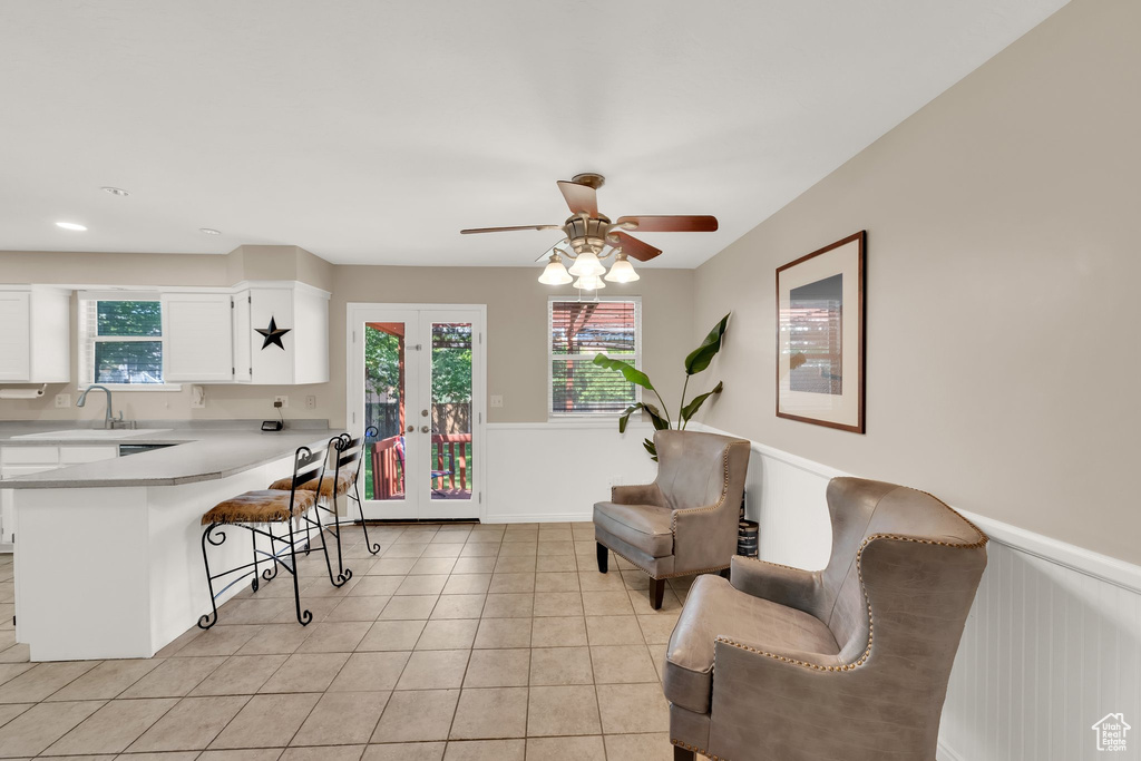 Kitchen featuring a breakfast bar area, light countertops, white cabinetry, a peninsula, and a sink