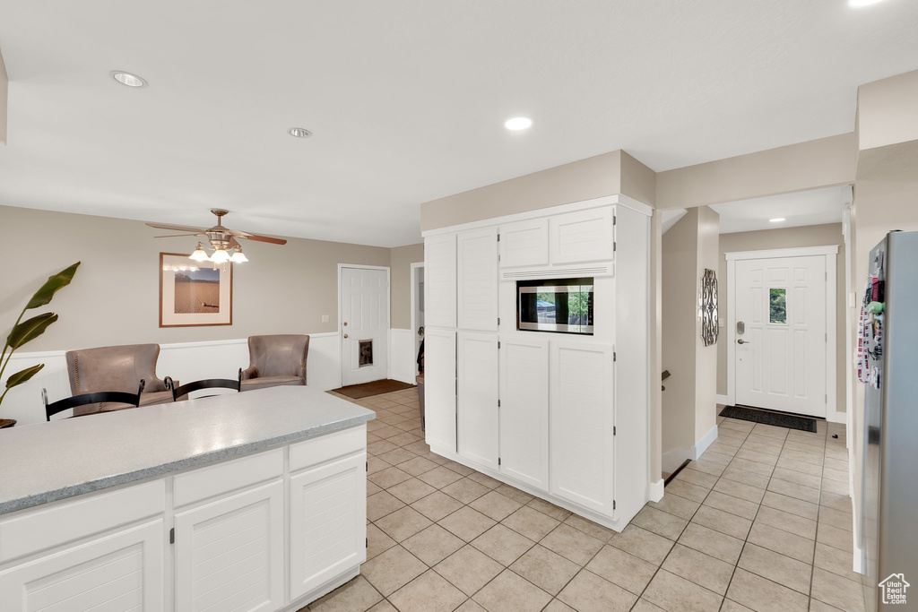Kitchen featuring light tile patterned floors, ceiling fan, freestanding refrigerator, light countertops, and recessed lighting